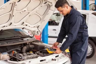 Car bonnet open with an engineer testing the engine using a diagnostic meter Car bonnet open with an engineer testing the engine using a diagnostic meter